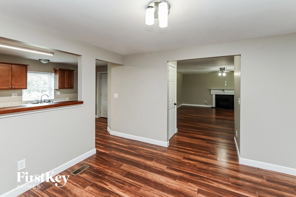 a renovated living room and kitchen with wood flooring and white walls