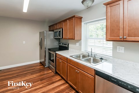 a kitchen with wood flooring and wooden cabinets and stainless steel appliances