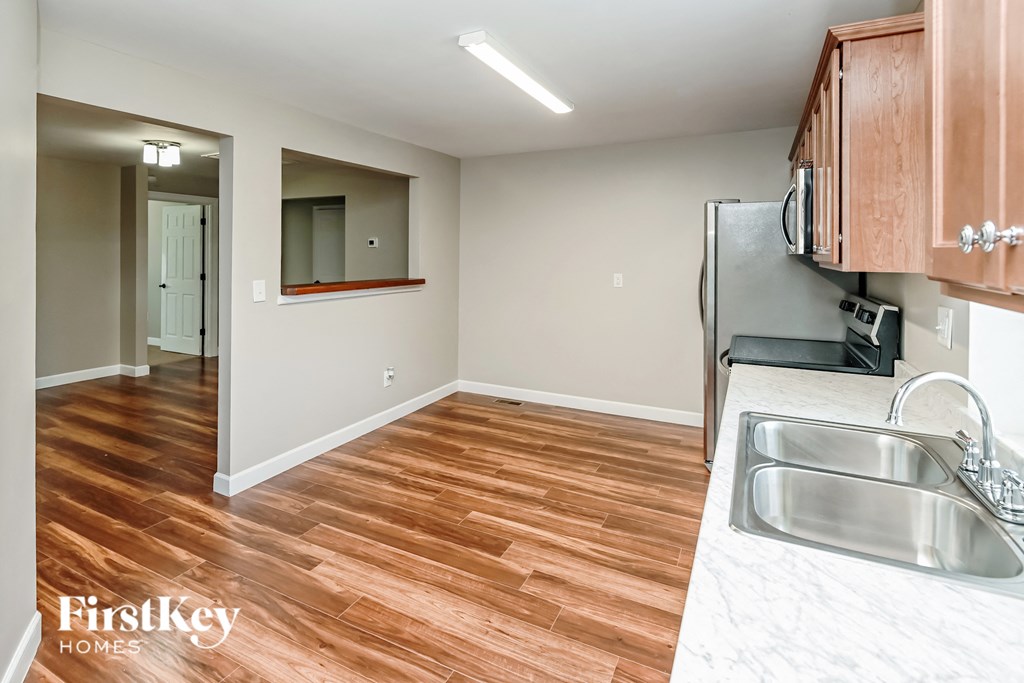 a renovated kitchen and living room with wood flooring and stainless steel appliances