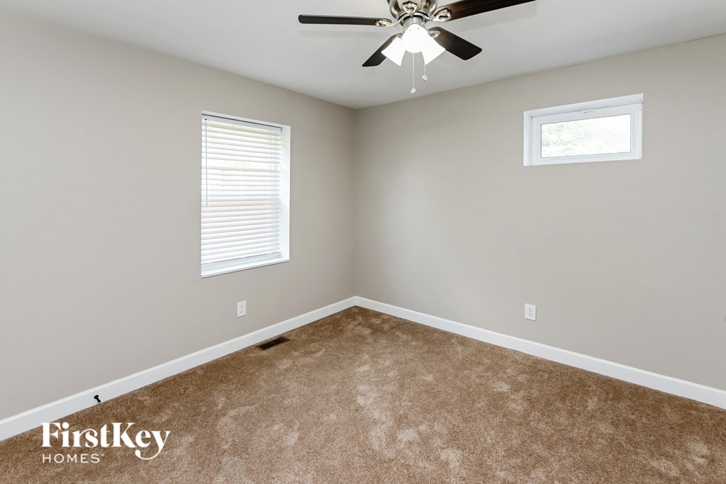 an empty room with a ceiling fan and two windows