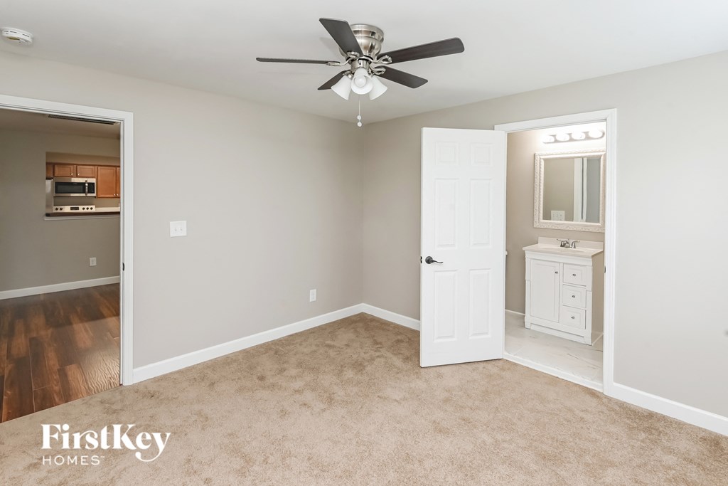 an empty bedroom with a ceiling fan and a bathroom