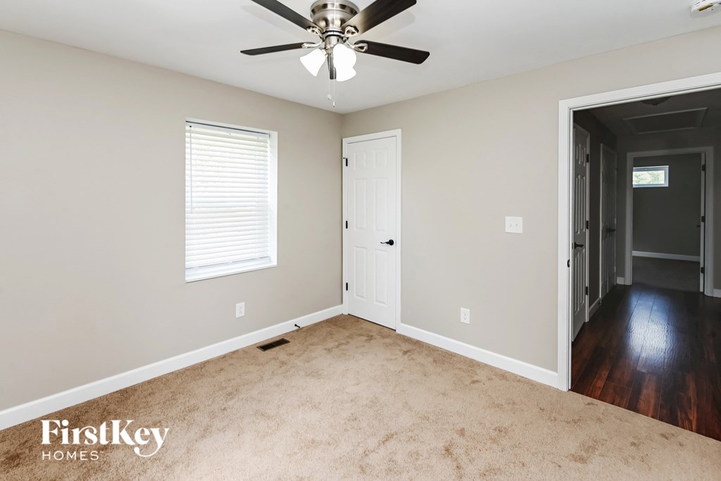 an empty room with a ceiling fan and a door to a hallway