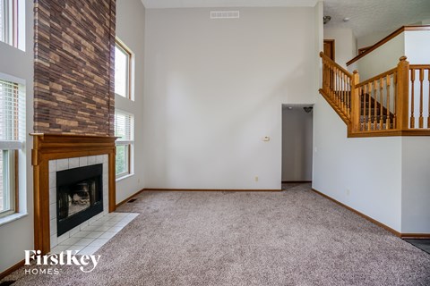 an empty living room with a fireplace and a staircase