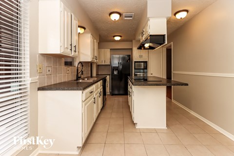 a kitchen with white cabinets and black counter tops
