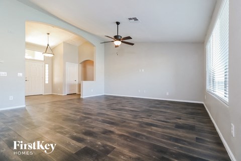 an empty living room with wood floors and a ceiling fan