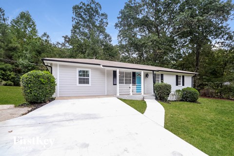 a white bungalow with a white driveway and a blue door