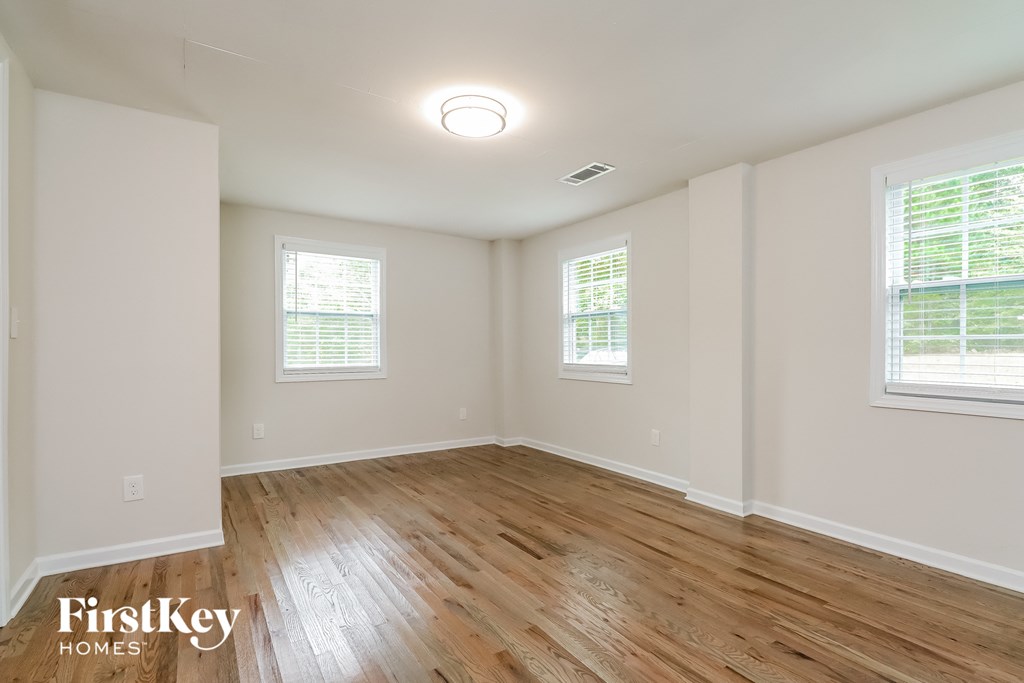 the spacious living room with wood floors and white walls