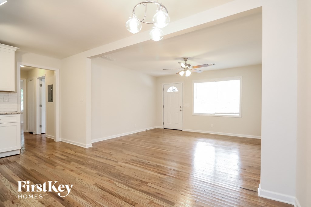 the living room and dining room with wood flooring and a ceiling fan