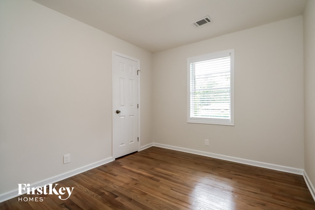 the upstairs bedroom with hardwood flooring and a white door