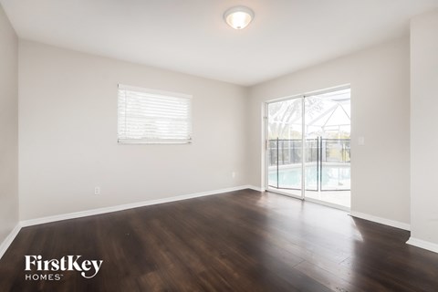 a living room with hardwood flooring and a sliding glass door to a pool