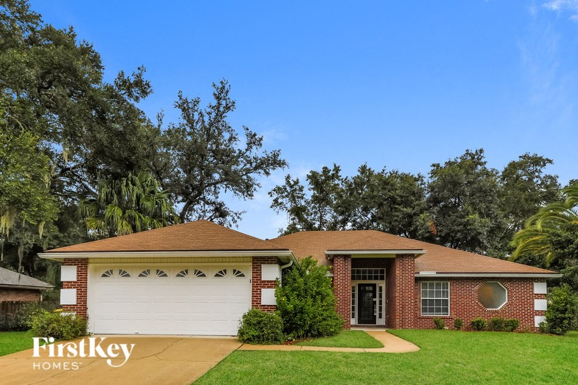 A house with a red brick exterior and a white garage door is for sale.