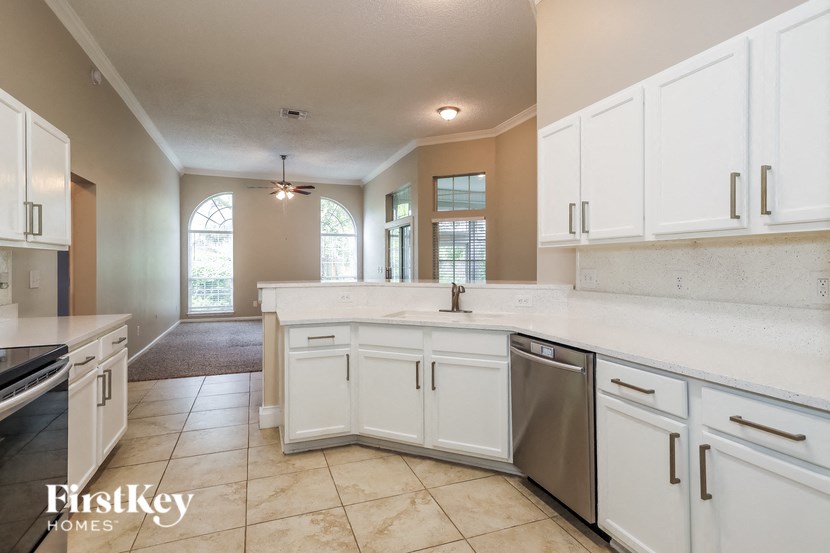 A kitchen with white cabinets and a tiled floor.