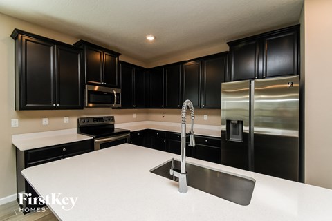 a kitchen with black cabinets and stainless steel appliances
