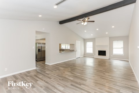 A spacious room with wooden flooring and a ceiling fan.