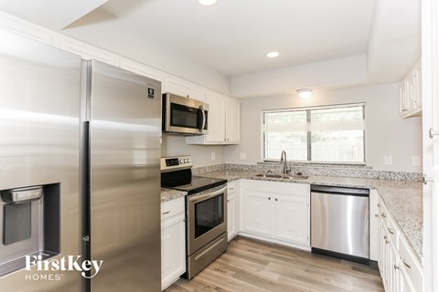 A kitchen with a stainless steel refrigerator and white cabinets.