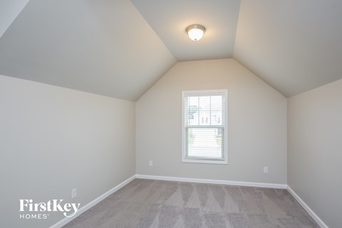 the bedroom has a vaulted ceiling and a window