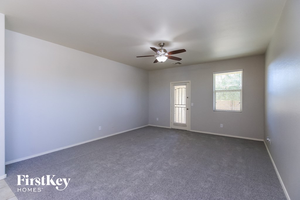 A room with a ceiling fan and a door leading to another room.
