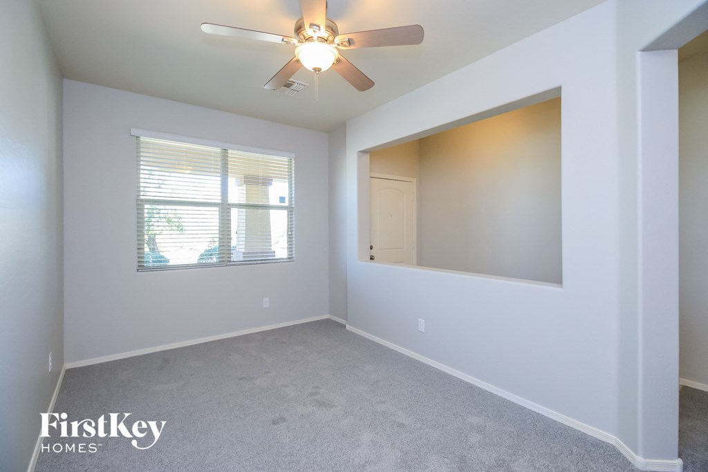 A room with a ceiling fan and a window with blinds.