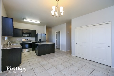 A kitchen with black cabinets and a white fridge is shown.