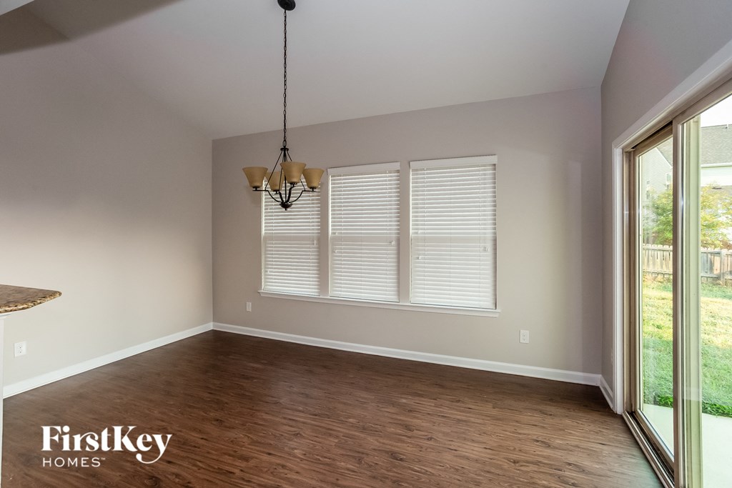 an empty dining room with wood floors and a window