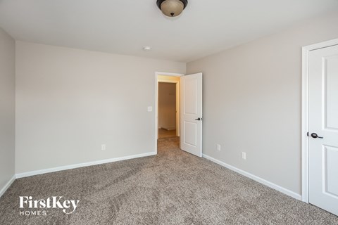 a bedroom with carpet and a door to a hallway