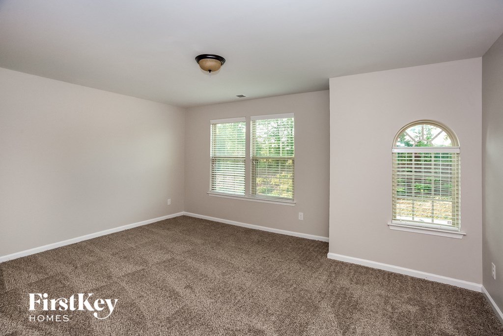 an empty room with carpet and two windows