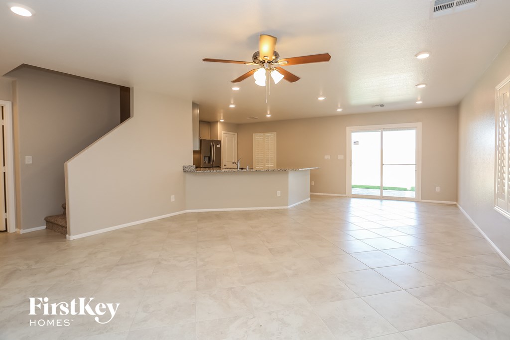 A spacious living room with a fan and a staircase.
