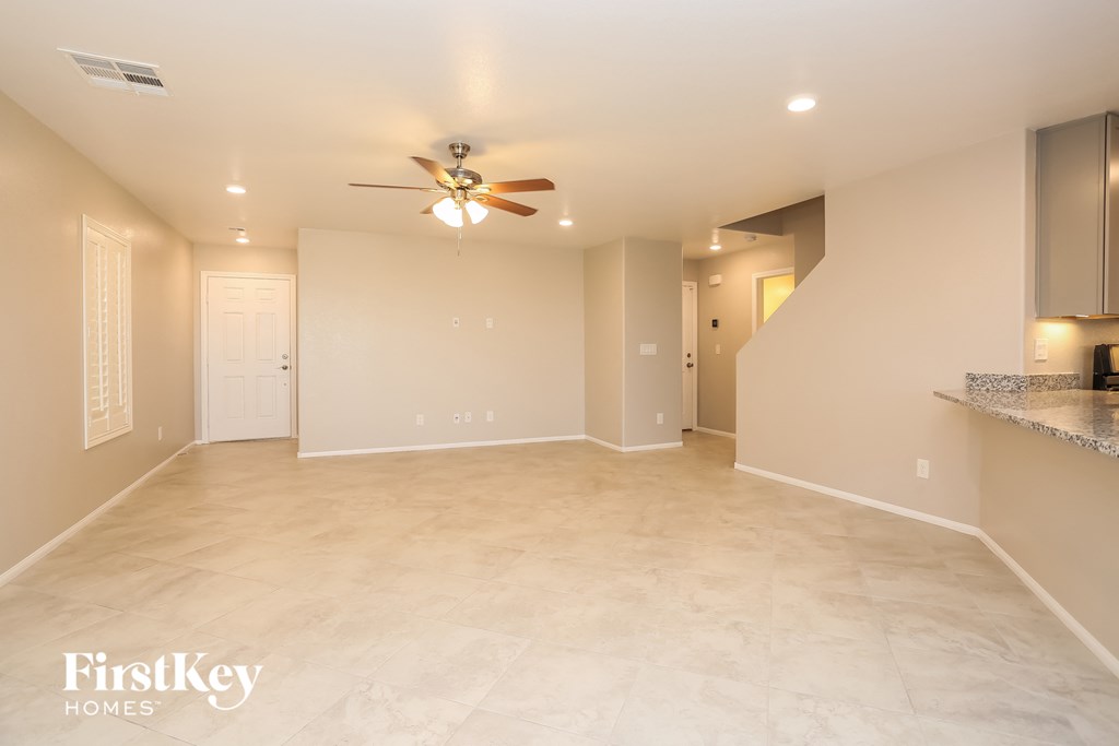 A spacious room with a ceiling fan and lighting fixtures.