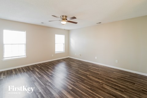A spacious room with wooden floors and a ceiling fan.