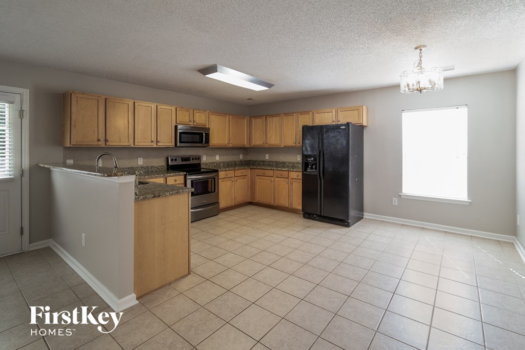 A kitchen with wooden cabinets and a black refrigerator.
