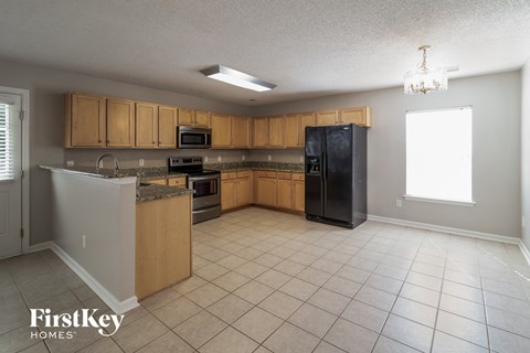 A kitchen with wooden cabinets and a black refrigerator.