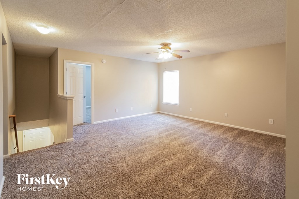 A spacious room with a carpeted floor and a ceiling fan.