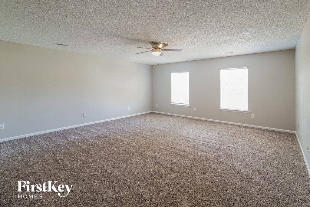 A room with a carpeted floor and a ceiling fan.