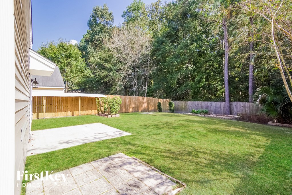 A backyard with a white fence and a small patch of dirt.