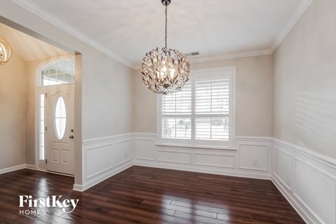an empty dining room with a large window and a chandelier