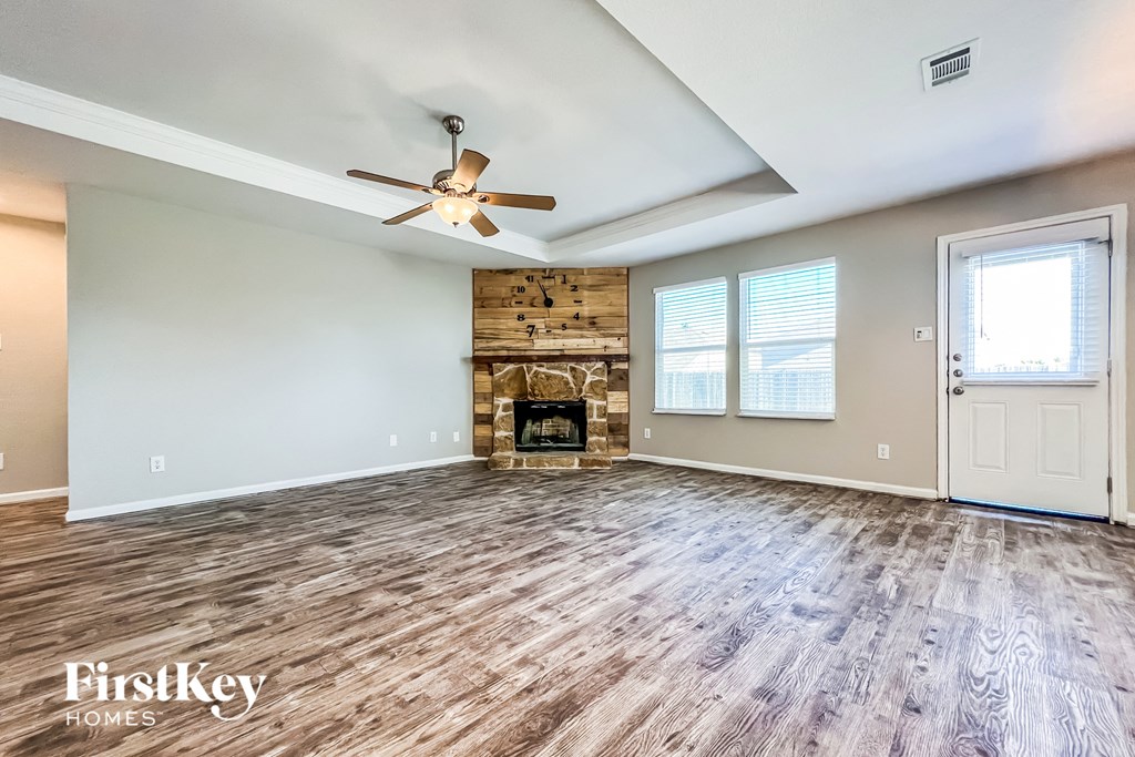 an empty living room with a fireplace and a ceiling fan