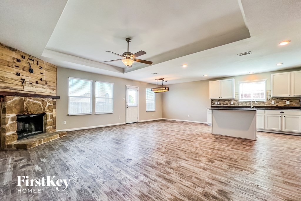an empty living room with a fireplace and a kitchen