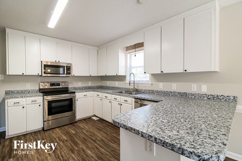 a kitchen with white cabinets and granite counter tops and