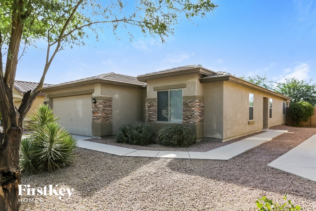 A house with a gravel driveway and a tree in the front yard.