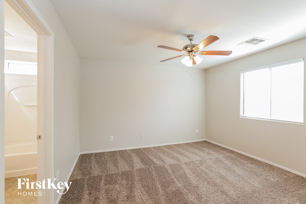 A room with a fan and carpeted floor.