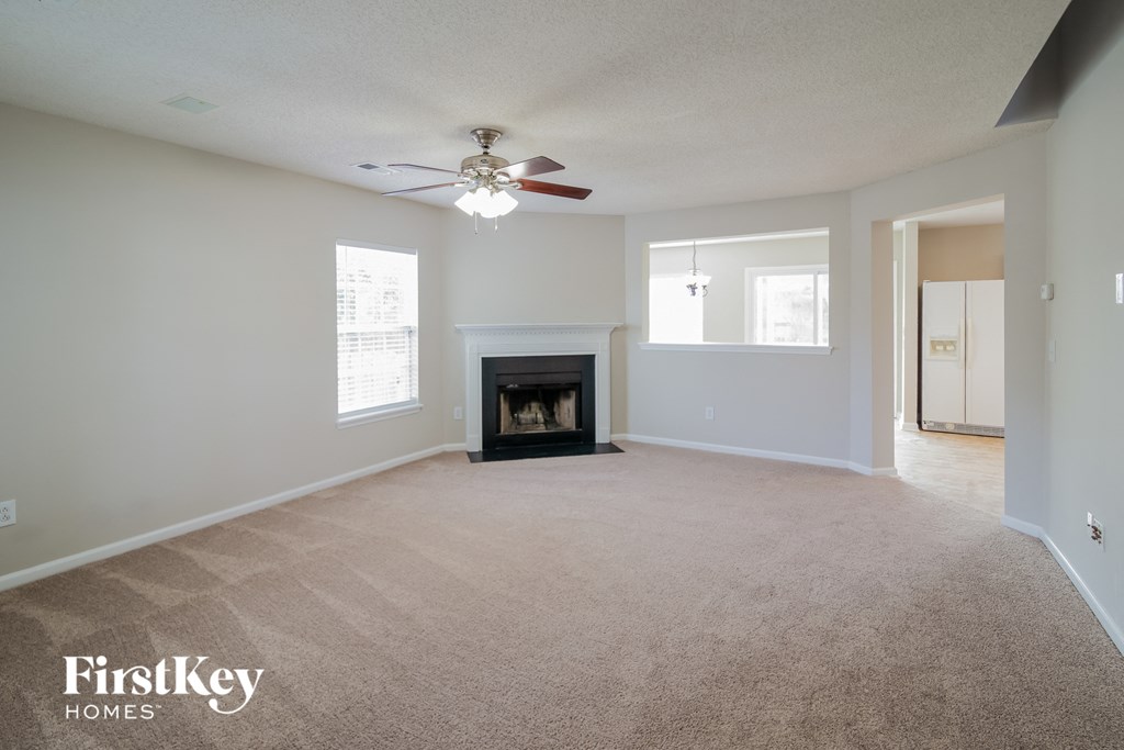 an empty living room with a fireplace and a ceiling fan