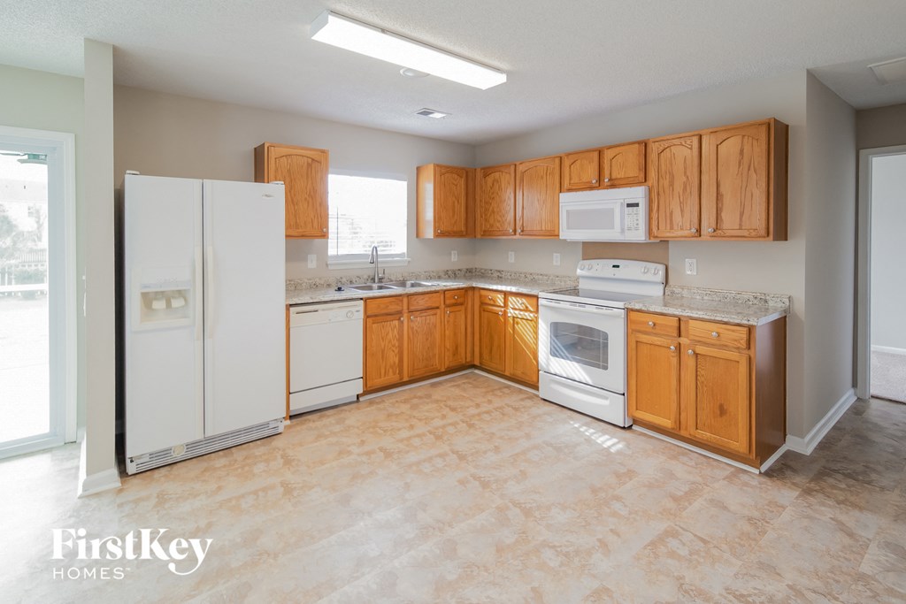 an empty kitchen with white appliances and wooden cabinets