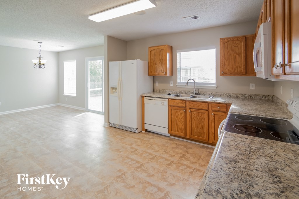 an empty kitchen with white appliances and wood cabinets