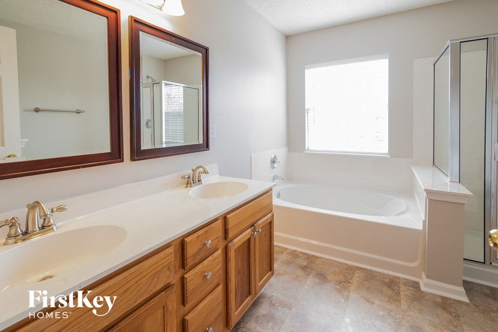 a bathroom with two sinks and a tub and two mirrors