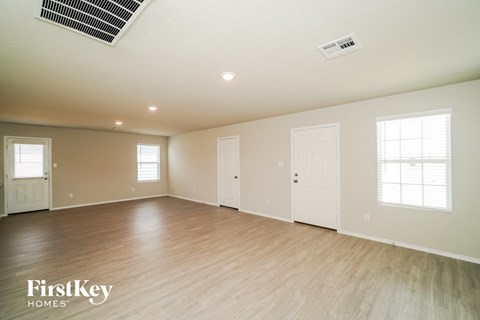 the spacious living room with wood flooring and white walls
