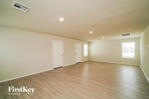 the spacious living room with hardwood flooring and white walls