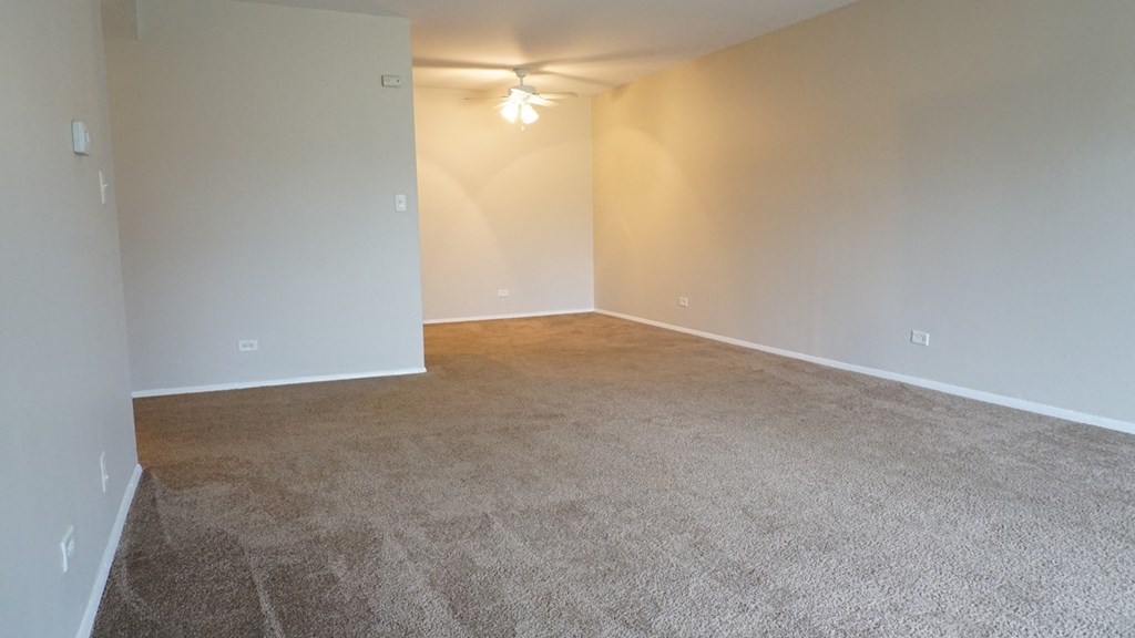 an empty living room with carpet and a ceiling fan