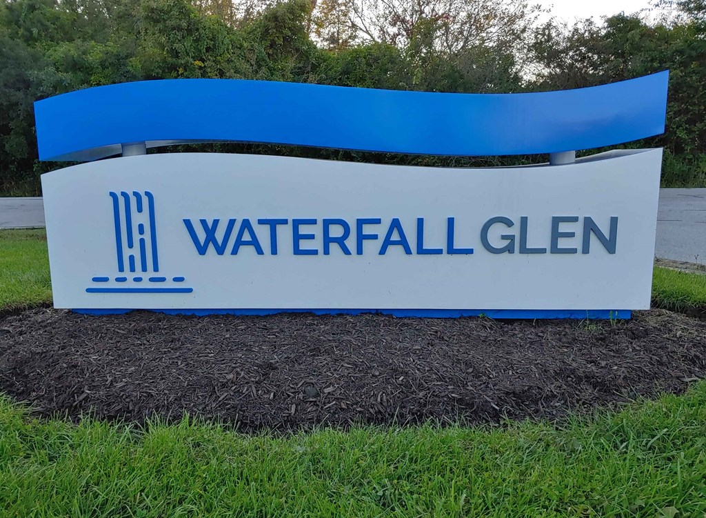 a sign for waterfall glen is shown in the grass