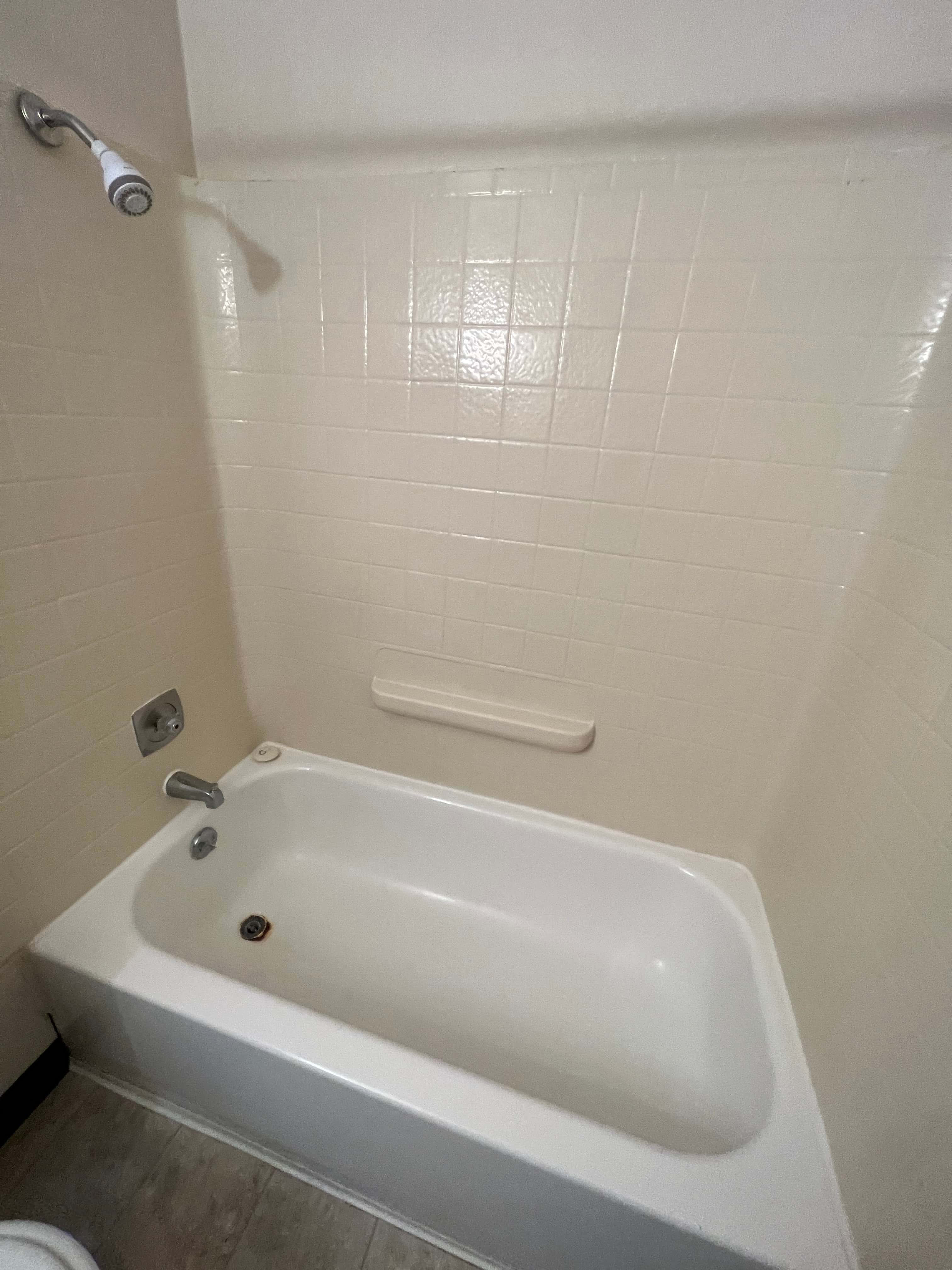 A white bathtub in a bathroom with a shower head.