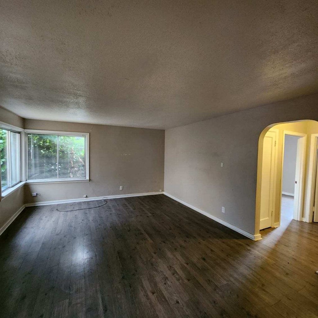 an empty living room with wood floors and a window